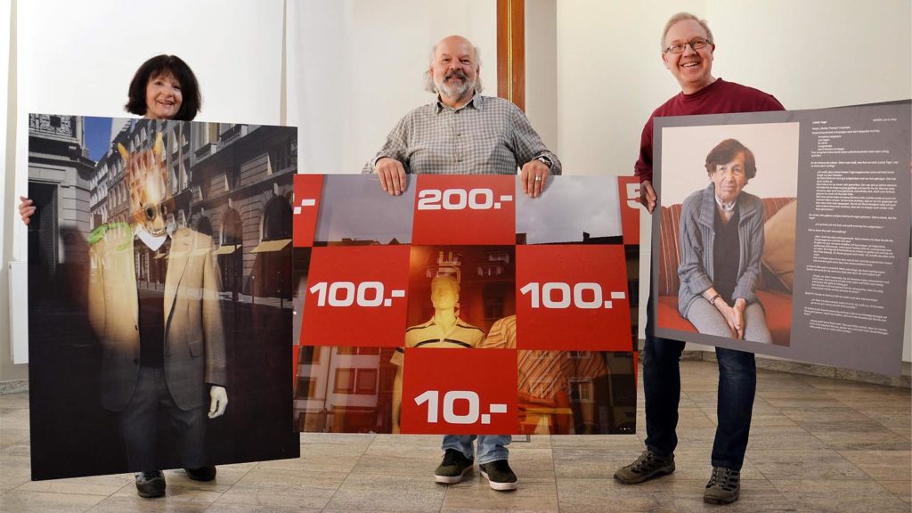 Ehefrau Helga Schulz-Laß (l.), Pfarrer i.R. und Fotograf Bernhard Laß (m.) und Presbyter Wolfgang Schneider (r.) präsentieren Bilder des Iserlohner Hobbyfotografen in der Ev. Erlöserkirche in Witten-Annen. (Foto: Christian Lukas)